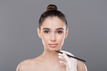 Doctor drawing lines on female patient's face before skin lifting
