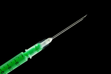 Syringe filled with green drug and dripping from the needle - isolated on black