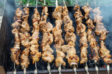 Appetizing fresh meat kebab with burnt crust is fried on the grill. Delicious food on a picnic. Traditional Russian shashlik on a barbecue skewer as top view. BBQ, meat, picnic