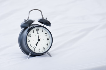 Alarm clock on white bedsheet.