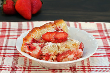 A serving of fresh baked strawberry cobbler garnished with strawberry slices.