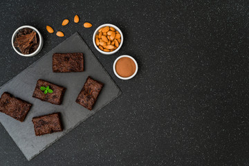 Dark chocolate and cocoa brownie fudge cakes dessert with mint against black and grey stone background