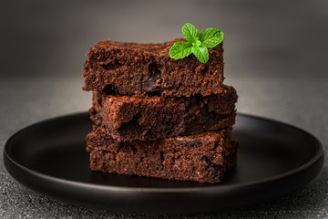 Dark chocolate and cocoa brownie fudge cakes dessert with mint against black and grey stone...