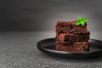 Dark chocolate and cocoa brownie fudge cakes dessert with mint against black and grey stone...