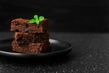 Dark chocolate and cocoa brownie fudge cakes dessert with mint against black and grey stone background