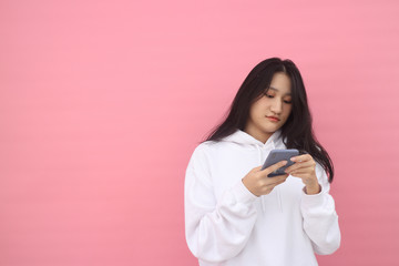 happy excited  glad to receive text message informing about salary, rejoices good news, stares at mobile phone, actively from happiness, Beautiful Asian models over  pink  background for advertising c