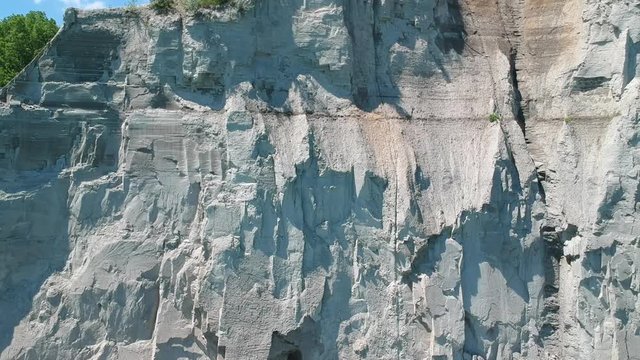 Aerial: flying backwards from close up view of the Scarborough bluffs white clay cliff to the lake Ontario at a slow pace, ending with scenic view of bluffs overlooking green cyan waters of the lake