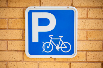 On the masonry facade of a building hangs a blue and white information sign that you can park your...