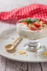 Glass bowl with yogurt, berries and mint in a bowl on a wooden table.