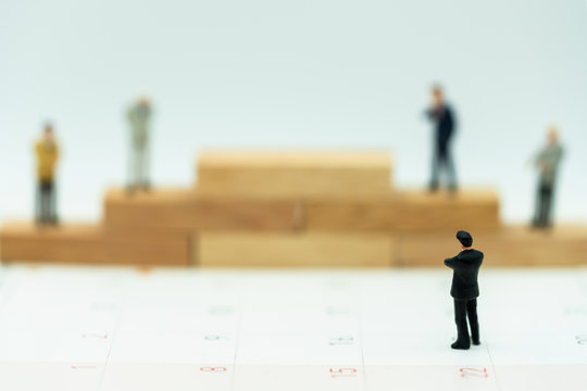 Miniature people: Business man standing on a wooden box.