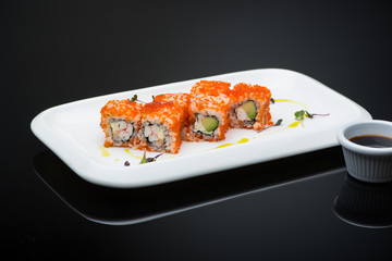 sushi in a plate on a black background with reflection. fish roll