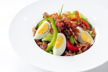 Fresh Caesar Salad with Deep-fried Bacon and Boiled Egg on White Porcelain Round Plate, Isolated on White Background with Shadow. Close Up High Angle Top View, Selective Focus at Food.