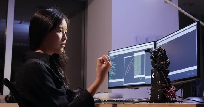 Asian woman try to controls robot hand at lab. Technology and innovation concept.