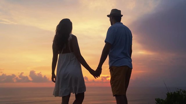 Silhouette of man and woman hugging, kissing on sunset background, slow motion