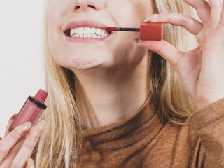 Happy cheerful woman using lips gloss