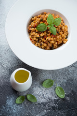 White plate with italian fregola pasta, high angle view on a grey stone background, studio shot