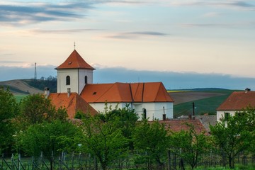 Obraz premium Moravian spring landscape of the village of Zeletice with fields, orchards and gardens, brick church of St. James, tiled houses