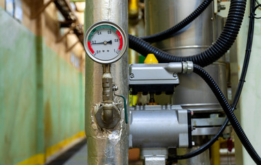 Low light view. The pressure gauge dial installed to the pipe wrapped with insulation. To control the temperature and pressure. Inside chemical factory.