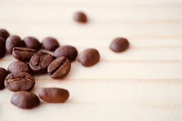 roasted coffee bean on light brown wooden texture with copy space, selective focus