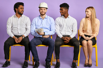 Obraz premium multicultural project group sitting and looking at construction engineer in safety helmet. Construction Concept