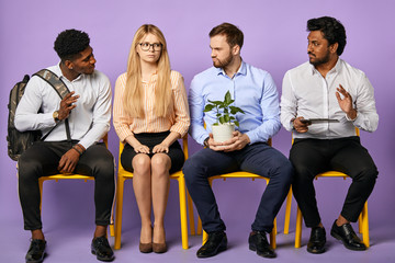 diverse multinational group of people sitting together and looking at each other waiting for job interview