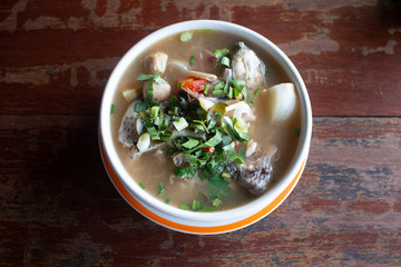 Spicy fish soup flavored with lemongrass and lime served on wooden table