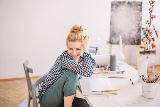 positive stylish female designer with hairbun laughing at something while working in the studio. close up photo.