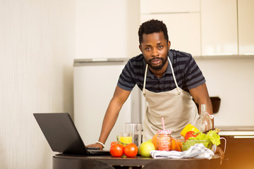 Man looking recipe on laptop in kitchen at home