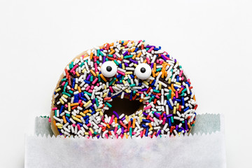 Funny shock face chocolate donut with sprinkles on a white background, creative minimal food concept