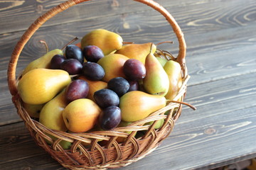 Ripe pears and plums are at the wicker basket .