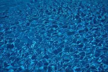 Swimming pool water surface with sparkling light reflections. Clear blue water from a swimming pool with very nice reflections.