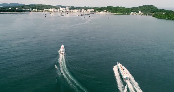 Speed boat on the sea with wake foam on blue water. High-quality stock video footage view from above, top view of cruise ship moving on the beach with ocean waves and sea foam to island