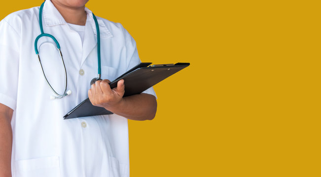 Doctor With Lab Coat On Yellow Background Holding A Clipboard.