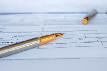 Low angle view of golden pen lying on white sheet of paper in a folder with another set of paperwork