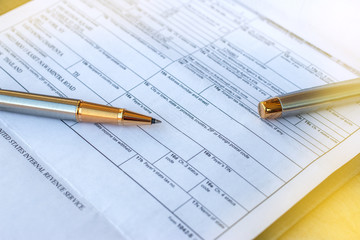 Low angle view of golden pen lying on white sheet of paper in a folder with another set of paperwork