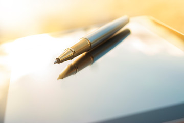 Low angle view of golden pen lying on tablet
