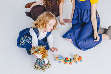 Three sisters having fun. Togertherness and friendship. Girls in long old fashioned dresses. Taking care of the youngest