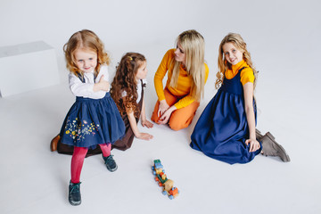 A mother with three cute daughters playing with wooden toy train. A family of four
