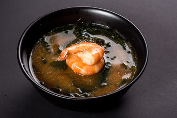 Hot miso soup with shrimp in bowl on black background. Japanese food