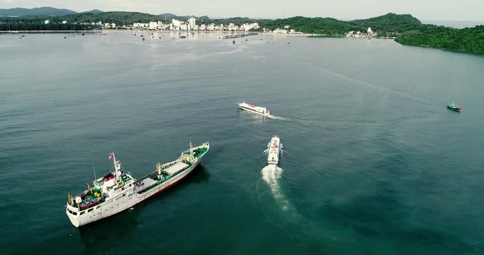 Top view of cruise ship go to the harbor, pier, dock at Ha Long bay, Ha Long city, Vietnam. High-quality stock video footage view from above, top view of cruise ship moving on the beach to island