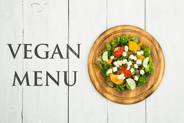 Fototapety  Koncepcja zdrowej żywności - sałatka ze świeżych warzyw z zielenią, tofu, pomidorami, ogórkiem i tekstem Menu wegańskie