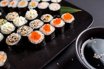 Japanese sushi rolls set served on black plate on dark background