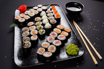 Japanese sushi rolls set served on black plate on dark background