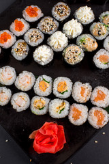 Japanese sushi rolls set served on black plate on dark background