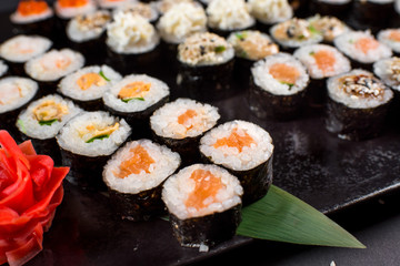 Japanese sushi rolls set served on black plate on dark background
