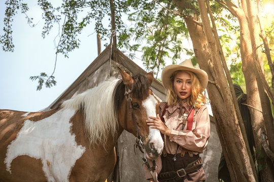 Beautiful Asian girl cowboy takes care of her horse with love and care.