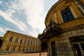 corner of a two-story house with a balcony. The old facade is yellow.