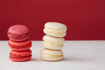 Stacks of crimson and vanilla macaroons on a red and white background. Close-up.