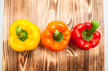 Colorful sweet pepper on wooden cutting board. Top view.