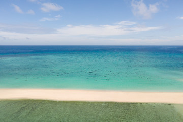 Sand beach island on a coral reef, top view. Atoll with an island of white sand.